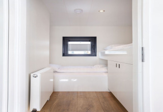 Dormitorio luminoso y moderno con literas y ventana en la casa flotante 'Agua Dolce' en los Países Bajos.