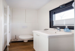 Baño moderno en la casa flotante 'Agua Dolce' en los Países Bajos, con inodoro, lavabo y ventana grande.