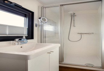 Salle de bain moderne sur la péniche Agua Dolce aux Pays-Bas avec douche, lavabo et fenêtre.
