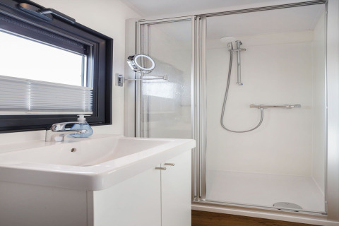 Baño moderno en la casa flotante Agua Dolce en los Países Bajos con ducha, lavabo y ventana.