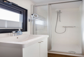 Baño moderno en la casa flotante Agua Dolce en los Países Bajos con ducha, lavabo y ventana.
