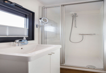 Salle de bain moderne sur la péniche Agua Dolce aux Pays-Bas avec douche, lavabo et fenêtre.