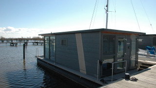 Moderne woonboot aan de steiger, foto genomen bij Boat No Name, rustig water en heldere lucht.