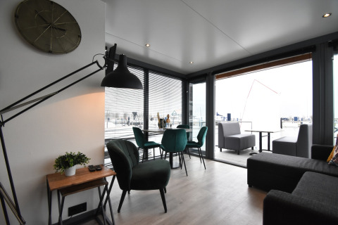 Modern living area on houseboat 'Boat' in the Netherlands with terrace view and stylish green chairs.