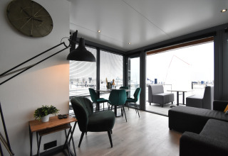 Modern living area on houseboat 'Boat' in the Netherlands with terrace view and stylish green chairs.