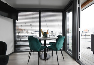 Modern dining area with green chairs aboard houseboat 'Boat' in the Netherlands with marina view.