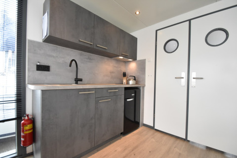 Modern grey kitchen with cabinets, sink, and appliances on houseboat 'Boat' in the Netherlands.