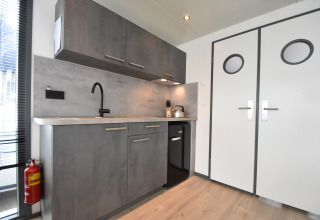 Modern grey kitchen with cabinets, sink, and appliances on houseboat 'Boat' in the Netherlands.