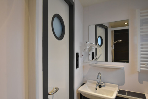 Bathroom on houseboat 'Boat' in the Netherlands, with round window door, mirror, and sink.