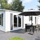 Veluwelodge ved Holiday park De Boshoek i Holland med hvid facade, terrasse, spisebord og parasol udenfor.