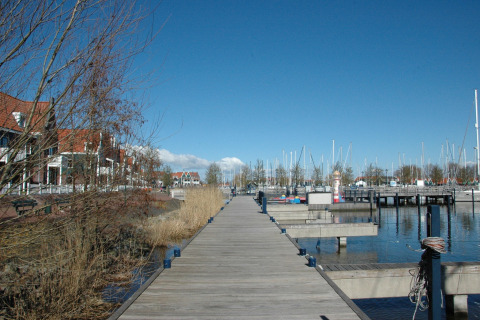 View from houseboat 'Boat' in the Netherlands, showing walkway, red-roofed houses, and marina.