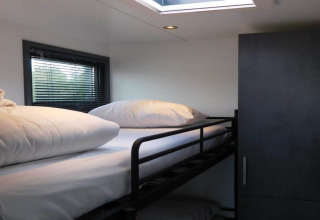 Modern bunk bed with white bedding and large pillows on houseboat 'Boat' in the Netherlands, window left.