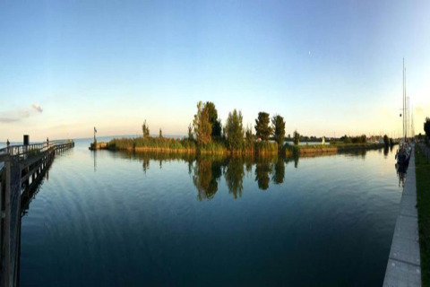 Panoramic photo taken from the houseboat 'Boat' in the Netherlands, showing calm water, trees, and sky.