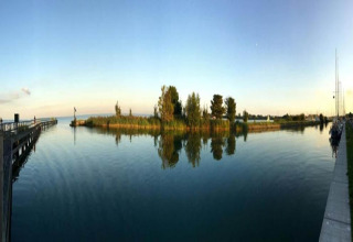 Panoramic photo taken from the houseboat 'Boat' in the Netherlands, showing calm water, trees, and sky.
