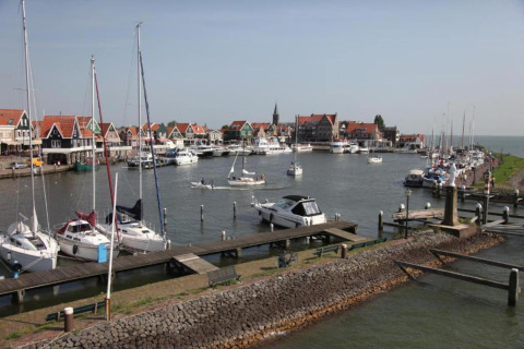 View of a harbor with sailboats and colorful houses by the water in the Netherlands, taken from a houseboat.