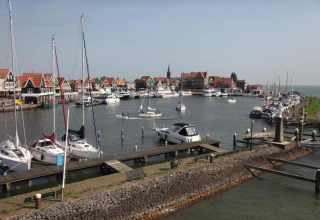 View of a harbor with sailboats and colorful houses by the water in the Netherlands, taken from a houseboat.