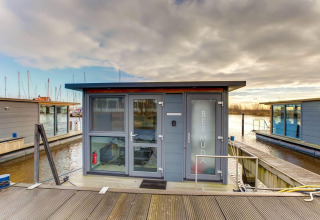 En moderne husbåd kaldet 'BERMUDA' fortøjet ved en havn nær Fort Edam i Volendam, Holland, under en overskyet himmel.