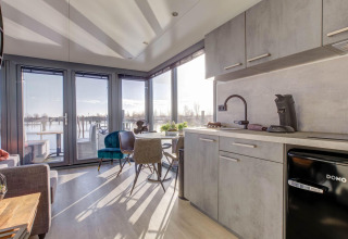 Soggiorno e cucina moderni su una houseboat a Volendam vicino a Fort Edam, Paesi Bassi, vista sull'acqua.
