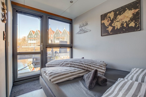 Dormitorio en una casa flotante en Volendam, Países Bajos, con vistas a casas tradicionales y al canal.