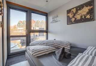 Camera da letto su una houseboat a Volendam, Paesi Bassi, con vista su case olandesi e il canale.