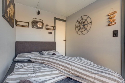 Dormitorio en una casa flotante en Volendam cerca de Fort Edam, decorado con detalles náuticos y ropa de cama a rayas.