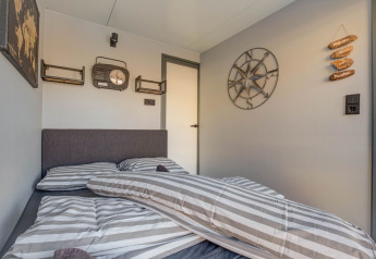Dormitorio en una casa flotante en Volendam cerca de Fort Edam, decorado con detalles náuticos y ropa de cama a rayas.