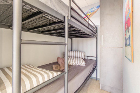 Schlafzimmer mit Etagenbett, gestreiften Kissen, Surfbrett und Schrank auf Hausboot in Volendam, Niederlande.
