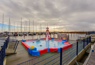 Udsigt over en legeplads med vandtema og lystbådehavn bagved ved Houseboat i Volendam, Holland.