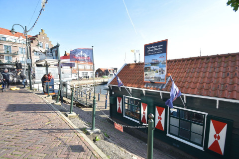 Casa flotante atracada en Volendam con ventanas rojas y tejado de tejas, cerca de Fort Edam, Países Bajos.