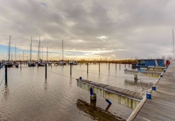 Casa flotante en un puerto deportivo cerca de Fort Edam en Volendam, Países Bajos, con cielo nublado.