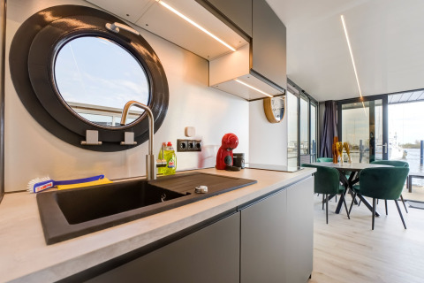 Cucina moderna su houseboat «La Belle Vie» nei Paesi Bassi, oblò rotondo e sala da pranzo vista acqua.