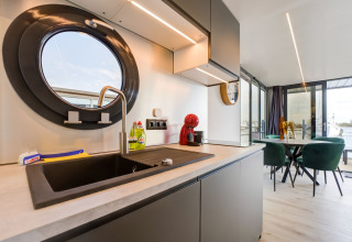 Cucina moderna su houseboat «La Belle Vie» nei Paesi Bassi, oblò rotondo e sala da pranzo vista acqua.