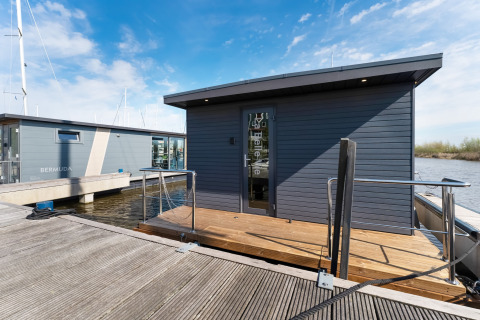 Casa galleggiante moderna La Belle Vie nei Paesi Bassi, ormeggiata con terrazza in legno.