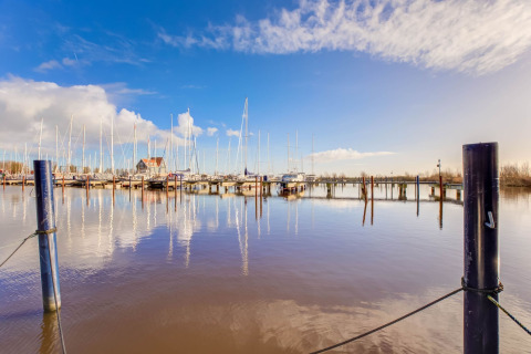 Vista sul porto con barche a vela e houseboat a Volendam vicino a Fort Edam, Paesi Bassi, cielo sereno.