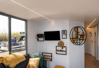 Soggiorno elegante sulla houseboat La Belle Vie nei Paesi Bassi, con arredi moderni e vista sul porto.