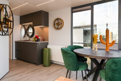 Cucina e sala da pranzo moderne sulla casa galleggiante 'La Belle Vie' nei Paesi Bassi, sedie verdi e tavolo tondo.