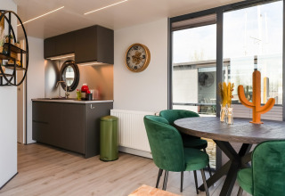 Cucina e sala da pranzo moderne sulla casa galleggiante 'La Belle Vie' nei Paesi Bassi, sedie verdi e tavolo tondo.