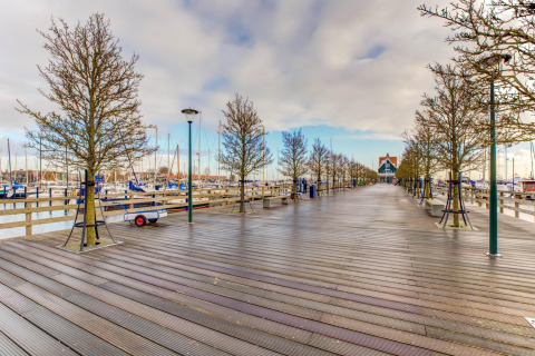 Muelle de madera con árboles y farolas junto al puerto deportivo en Volendam, cerca de Fort Edam, Países Bajos.