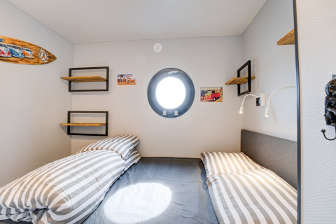 Camera da letto sulla houseboat 'La Belle Vie' nei Paesi Bassi con oblò e biancheria a righe.