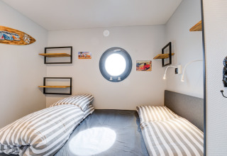Camera da letto sulla houseboat 'La Belle Vie' nei Paesi Bassi con oblò e biancheria a righe.