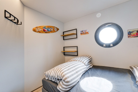 Camera moderna sulla houseboat 'La Belle Vie' nei Paesi Bassi con oblò rotondo e decorazione da spiaggia.