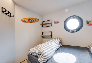 Camera moderna sulla houseboat 'La Belle Vie' nei Paesi Bassi con oblò rotondo e decorazione da spiaggia.