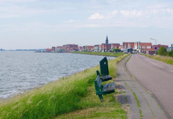 Strada costiera con panchine verdi sull’acqua e vista su Volendam nei Paesi Bassi.