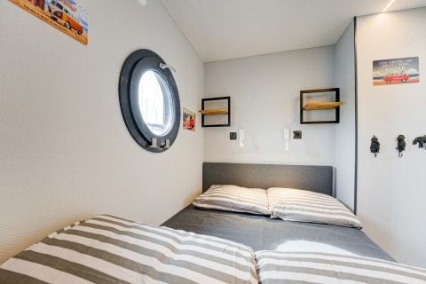 Camera da letto sulla houseboat La Belle Vie nei Paesi Bassi, con letto matrimoniale e oblò tondo.
