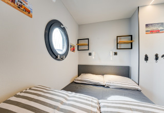 Camera da letto sulla houseboat La Belle Vie nei Paesi Bassi, con letto matrimoniale e oblò tondo.