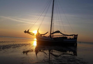 Casa flotante cerca de Fort Edam en los Países Bajos al atardecer, reflejada en aguas tranquilas y poco profundas.