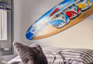 Decorazione con tavola da surf e van colorati con la scritta 'gone Surfing' in camera su una houseboat.