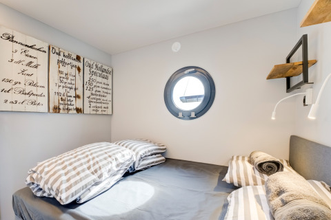 Camera accogliente sulla houseboat 'La Belle Vie' nei Paesi Bassi con oblò rotondo e arredo moderno.