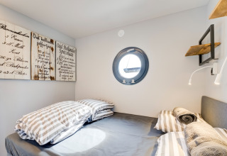Camera accogliente sulla houseboat 'La Belle Vie' nei Paesi Bassi con oblò rotondo e arredo moderno.