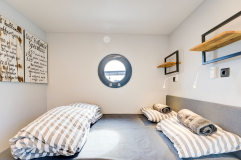 Accogliente camera da letto sulla houseboat 'La Belle Vie' nei Paesi Bassi con oblò e letti a righe.